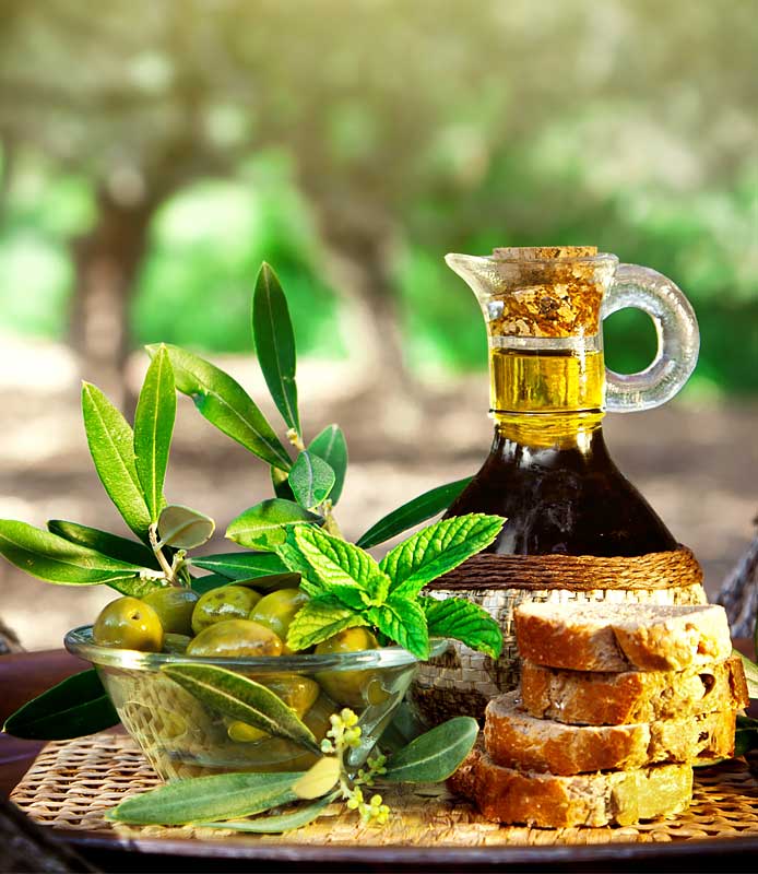 Bodegón natural de bote de AOVE, aceitunas y rebanadas de pan.